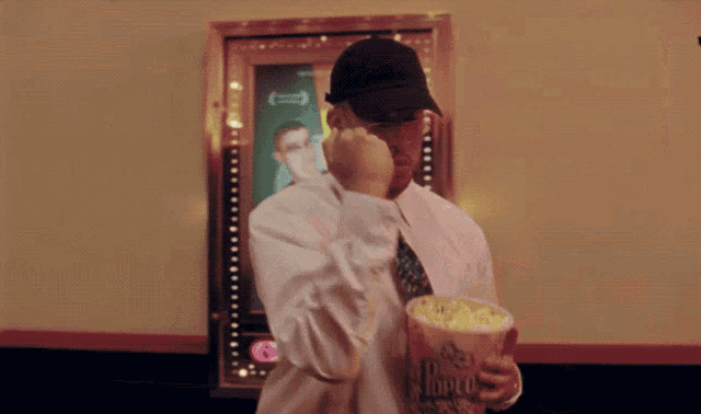 a man in a white shirt and tie is holding a bag of popcorn