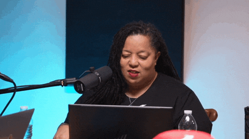a woman sitting in front of a microphone with a laptop in front of her