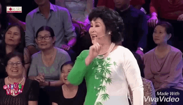 a woman in a green and white dress is standing in front of a crowd .