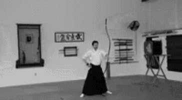 a black and white photo of a man holding a bow and arrow in a gym