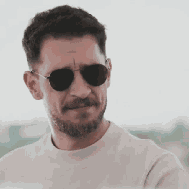 a man with a beard wearing sunglasses and a white t-shirt