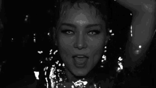 a black and white photo of a woman in the water looking at the camera .