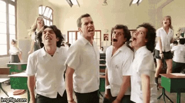a group of students are standing in a classroom with their mouths open and laughing .