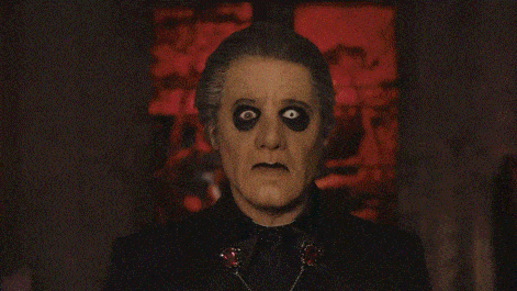 a man in a black suit with black eye makeup and a bow tie