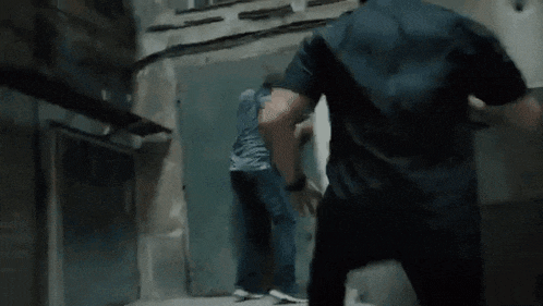 a man in a black shirt is running through a dark hallway .