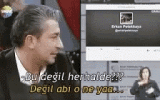 a man in a suit is talking to a woman in sign language while looking at a computer screen .