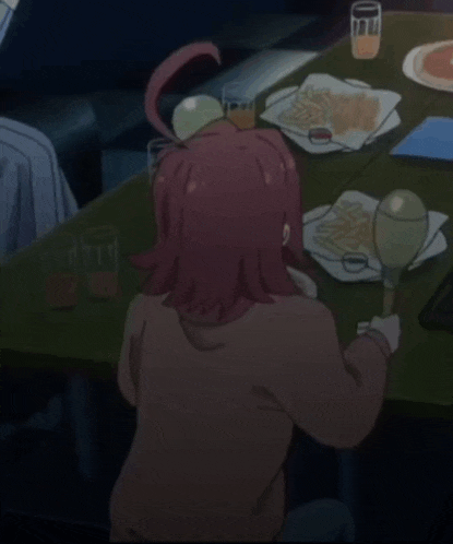 a girl with red hair is sitting at a table with a bottle of champagne