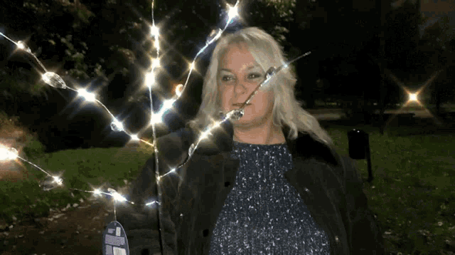 a woman is standing in front of a sign that says christmas lights