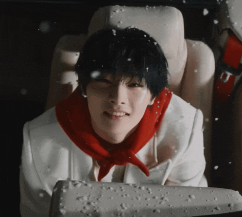 a young man wearing a red scarf is sitting in a car seat