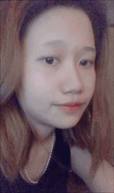 a close up of a girl 's face with a pearl necklace