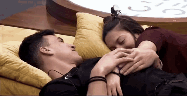a man and a woman are laying on a couch and the woman is touching the man 's stomach