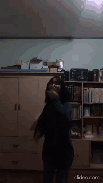 a woman is dancing in a room with a clipeo.com watermark
