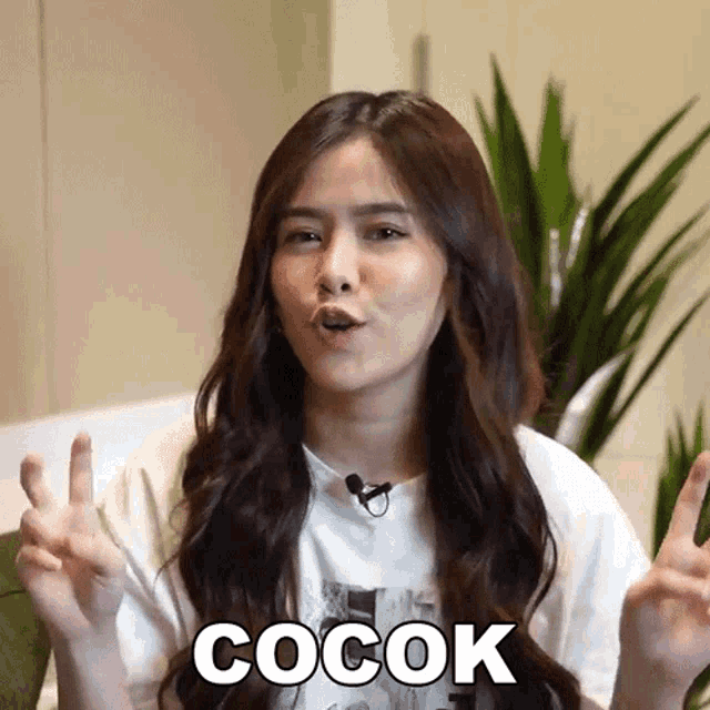 a woman with long hair is wearing a white shirt with the word cocok on it .