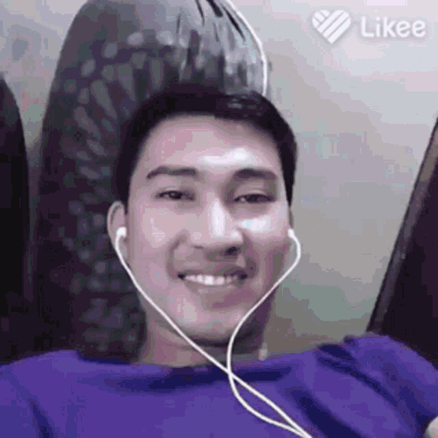 a man wearing headphones and a purple shirt is smiling and looking at the camera .
