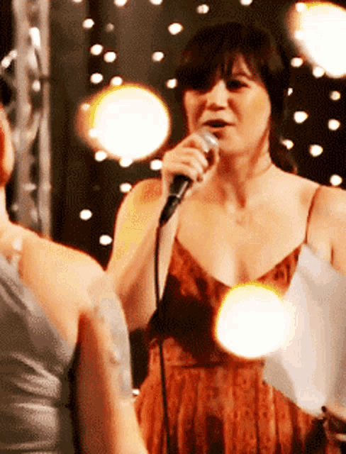 a woman is singing into a microphone while another woman watches
