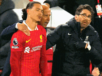 a soccer player wearing a red shirt that says standard chartered on it