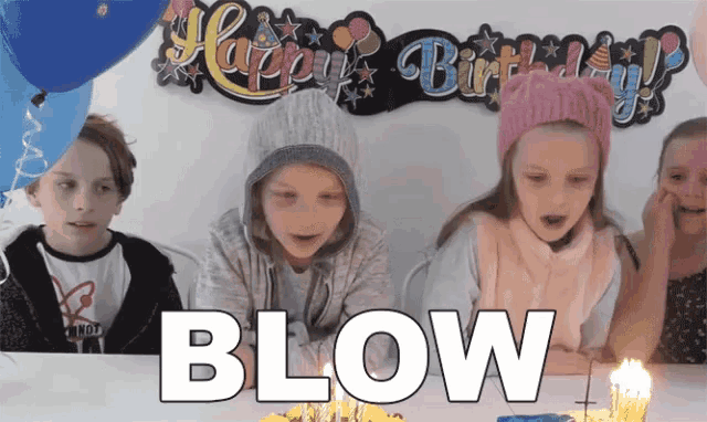 a group of children blowing out candles in front of a happy birthday sign ..