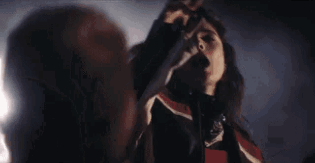 a woman is dancing in front of a crowd at a concert in a dark room .