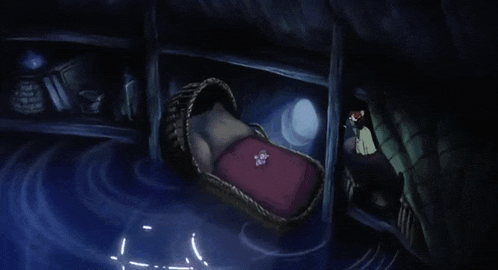 a wicker crib with a red blanket and a small teddy bear on it