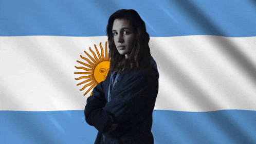 a woman stands in front of a blue and white flag