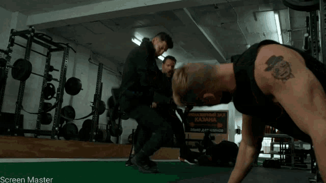a man with a tattoo on his arm is doing push ups in front of a sign that says screen master