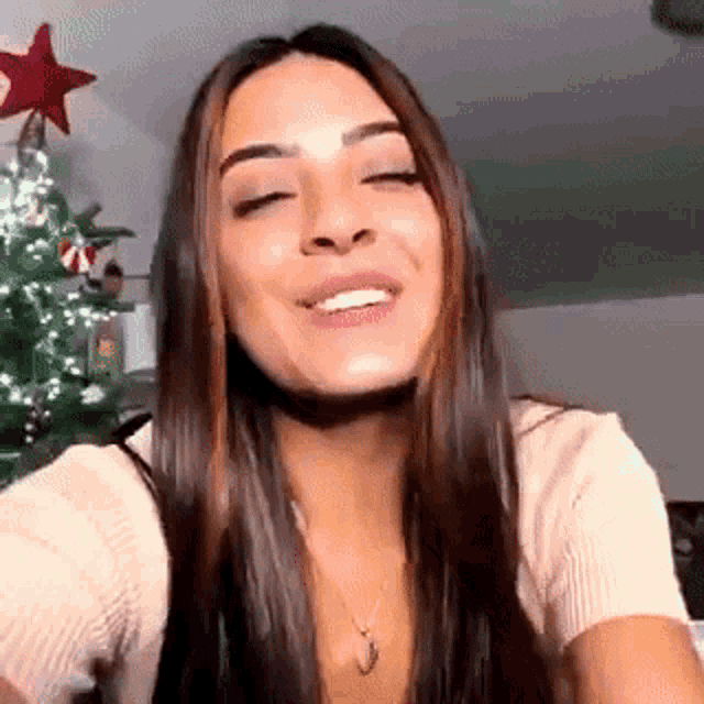 a woman is smiling in front of a christmas tree with a red star on top .