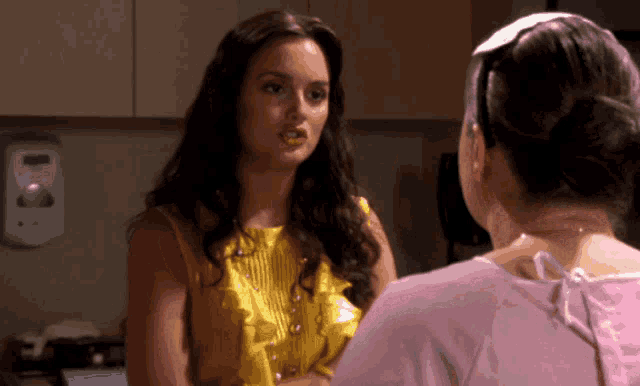 a woman in a yellow top talks to a woman in a pink shirt
