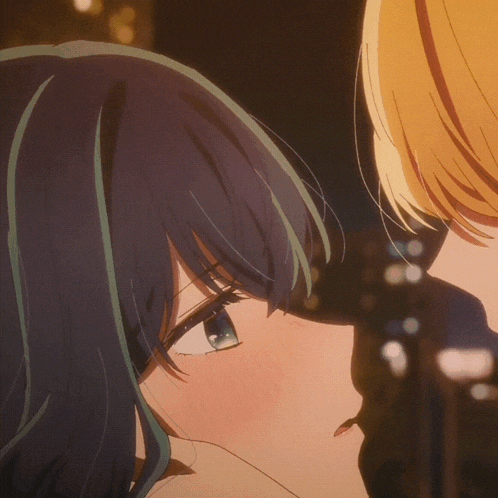 a close up of a girl with blue eyes kissing another girl with blonde hair