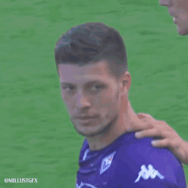 a man wearing a purple diacom jersey holds his fist up