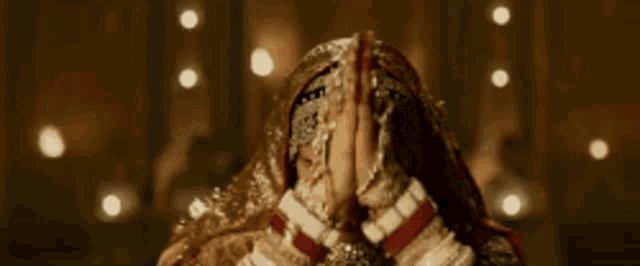 a woman in a traditional indian dress is praying with her hands together .