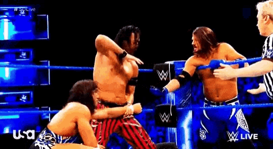 a group of wrestlers are fighting in a wrestling ring while a referee watches .