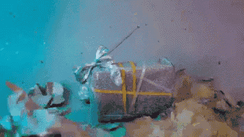 a gift box with a bow is floating on top of a pile of trash in the water .