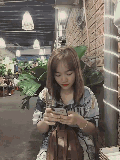 a girl is looking at her phone while sitting in a restaurant