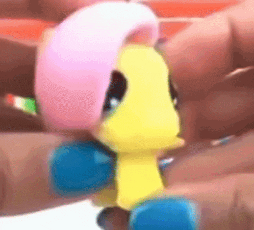 a close up of a person holding a toy pony with a pink mane .
