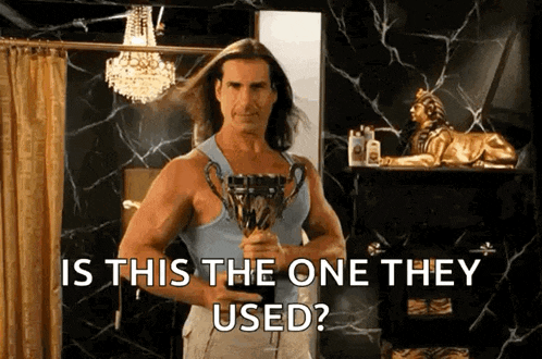 a man with long hair is holding a trophy in a bathroom and asking is this the one they used