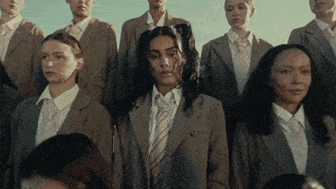 a woman in a suit and tie stands in a crowd of people
