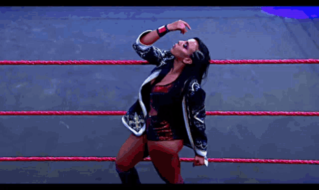 a woman is standing in a wrestling ring with her hand on her face