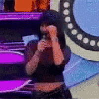 a man is singing into a microphone on a stage while covering his face .