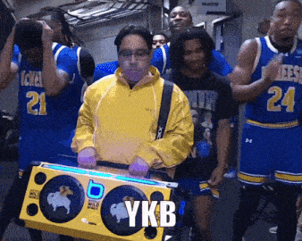 a man in a yellow jacket is carrying a box that says ykb on it