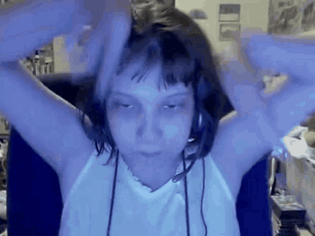 a girl wearing headphones and a white shirt is sitting in front of a computer screen .