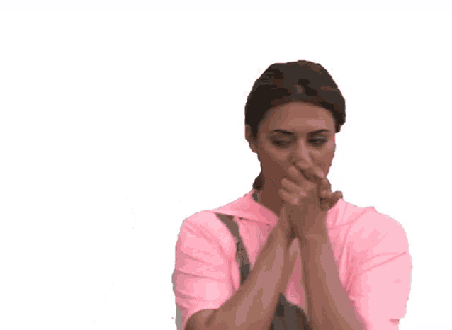 a woman in a pink shirt is praying with her hands folded