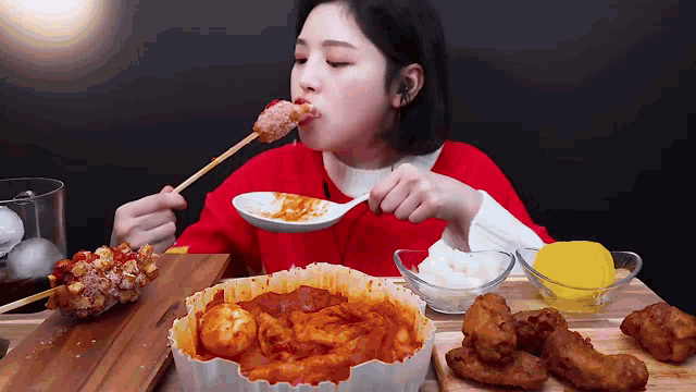 a woman is sitting at a table eating food with a spoon .
