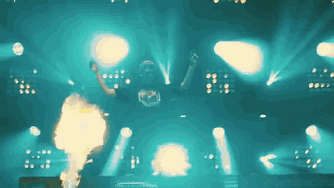 a group of people are dancing on a stage with fire coming out of them
