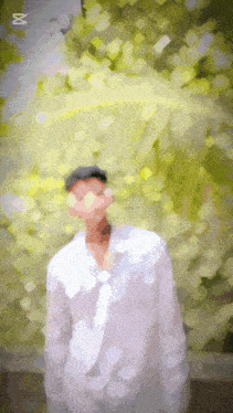 a blurry picture of a man in a white shirt with the letter x on the bottom right
