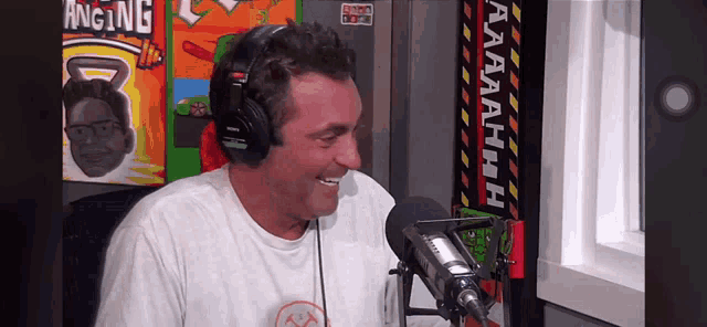 a man wearing headphones is sitting in front of a microphone and smiling .
