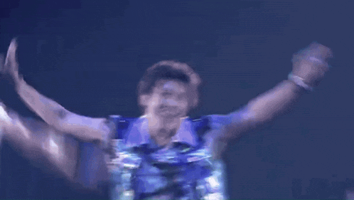 a group of people are dancing on a stage with a blue light shining on them