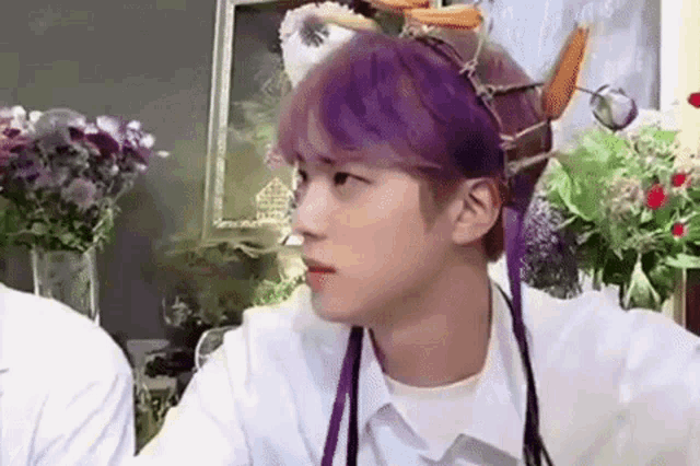 a young man with purple hair is wearing a white shirt and a headband .