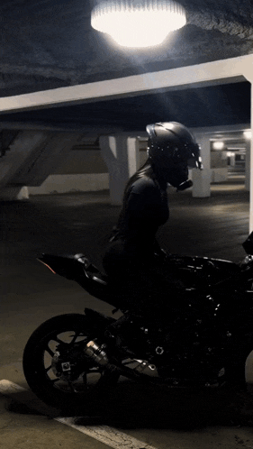 a person sitting on a motorcycle in a parking garage