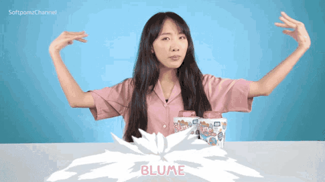 a woman in a pink shirt stands in front of a blue background with the word blume in pink