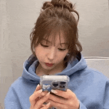 a woman in a blue hoodie is looking at her cell phone .